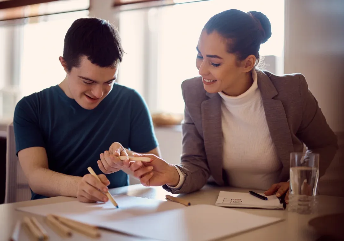 A man and woman collaborate on a project, sharing ideas and working together at a desk with laptops and documents.