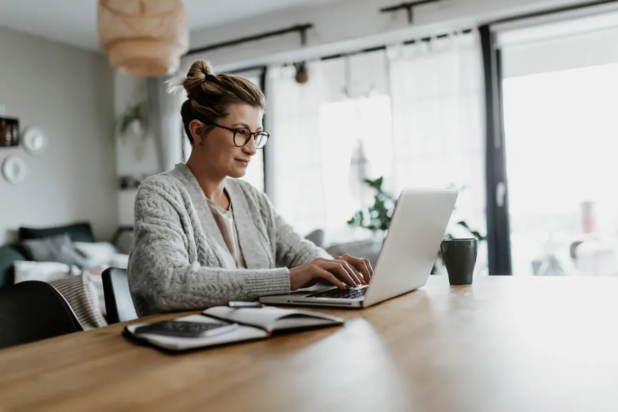 A woman engaged in her work on a laptop at home, showcasing a productive and comfortable workspace.