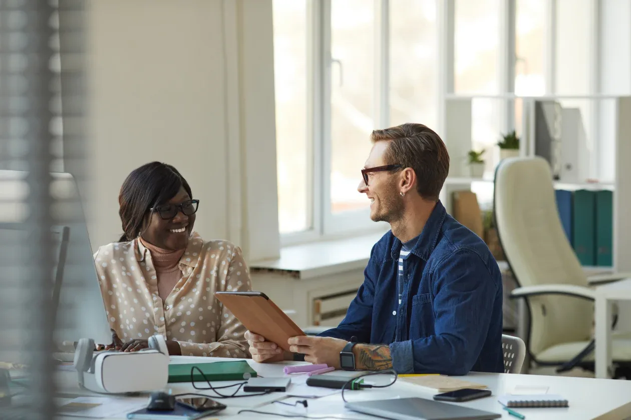 Two individuals seated at a desk, focused on a laptop, engaged in a collaborative work session.