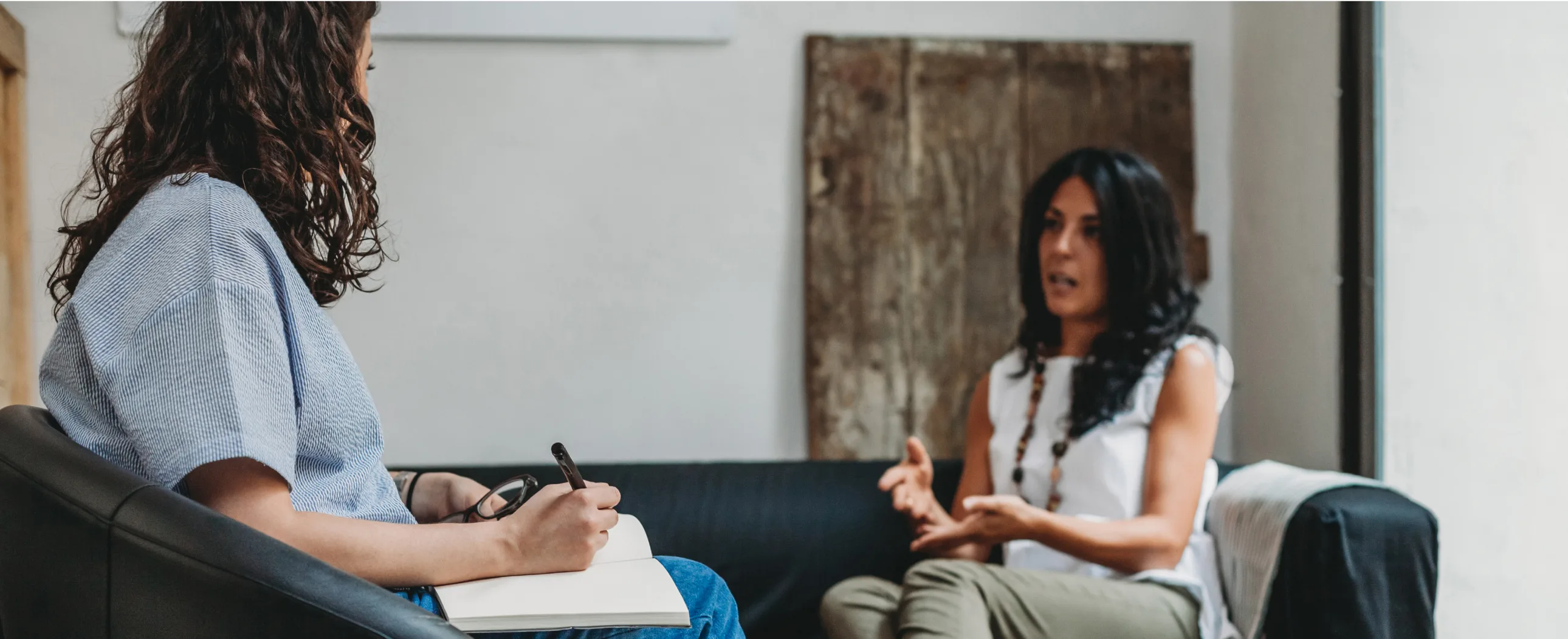 Two women seated on a couch, engaged in a lively discussion, showcasing friendship and connection.